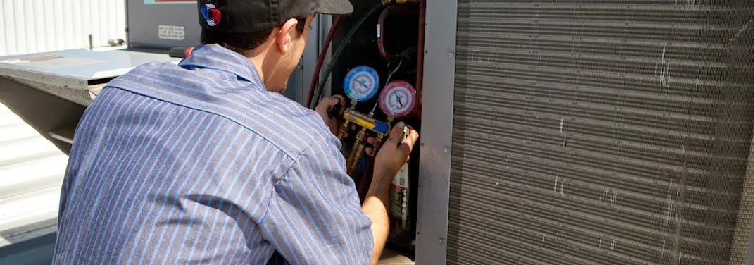 HVAC technician servicing a condenser unit in Ithaca