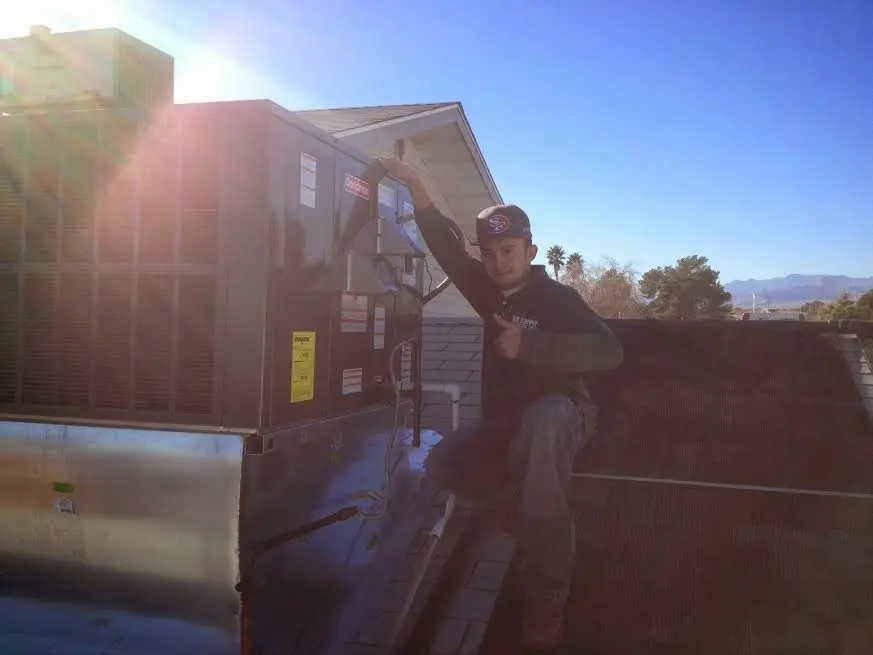 HVAC technician performing AC Tune-Up on a rooftop unit in Ithaca